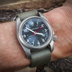 Wristwatch reading 5:00 PM held up next to a 24-hour clock dial, showing what 1700 military time looks like