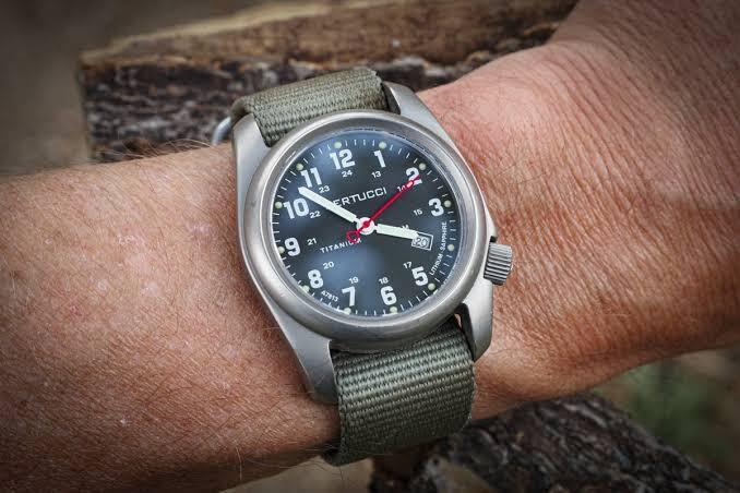 Wristwatch reading 5:00 PM held up next to a 24-hour clock dial, showing what 1700 military time looks like
