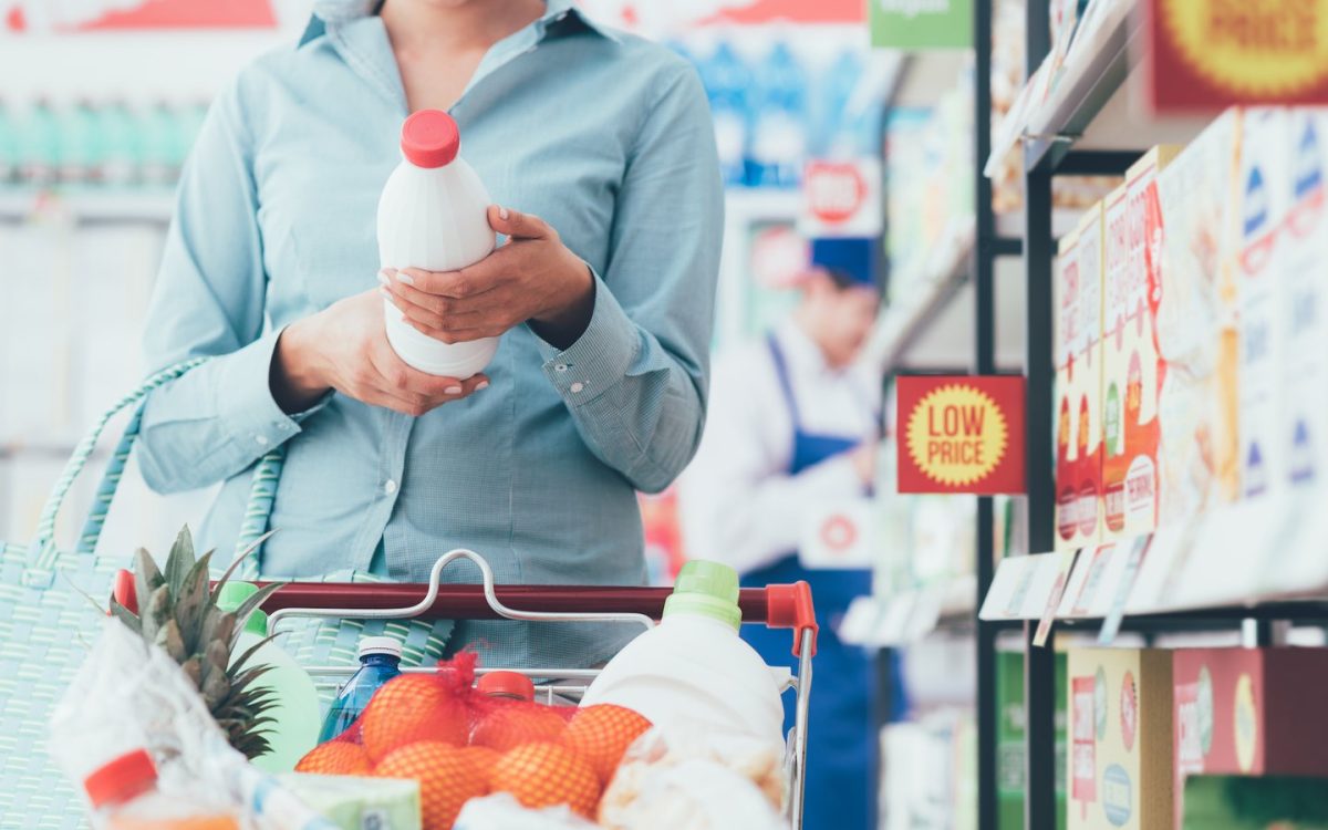 Grocery shopper reading the ingredients label on a jar of sauce, checking the halal food meaning behind everyday products