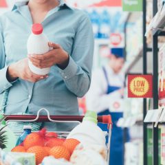Grocery shopper reading the ingredients label on a jar of sauce, checking the halal food meaning behind everyday products
